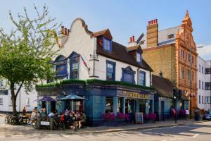 un grupo de personas sentadas afuera de un edificio en The Foresters Arms, en Kingston upon Thames
