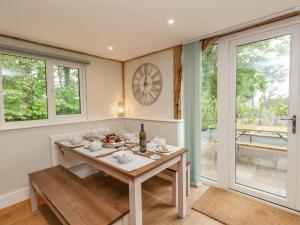 a dining room with a table and a clock on the wall at Roman Lodge in Weymouth