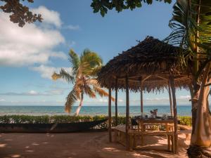 a beach with a table and a palm tree and the ocean at Dicilaba Lodge in Sainte Marie