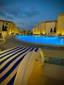 a bench in front of a swimming pool at night at شقة بقرية هلنان بورفؤاد in Chantier Island