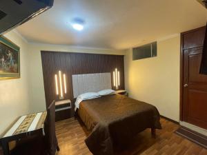 Un dormitorio con una cama y dos luces en la pared. en DON TITO Inn, en Puno