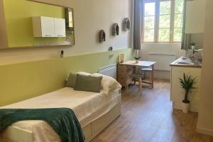 een slaapkamer met een bed, een bureau en een keuken bij Dina chic calme cosy in Saint Etienne