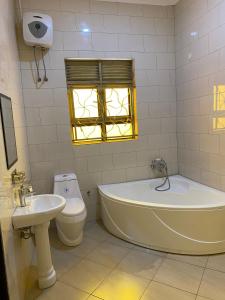 a bathroom with a tub and a toilet and a sink at MSGLakeview Guest House- Entebbe Bugiri in Kira +68 photos
