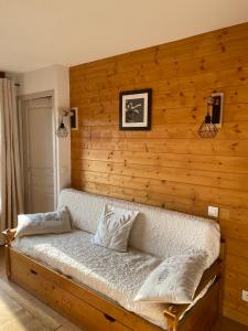 a bedroom with a wooden wall with a bed with pillows at L'Ecrin des Myrtilles - Appartement cosy - Piscine et vue montagne - Alpes - Val d'Arly - Aravis et Beaufortain in Flumet +60 photos
