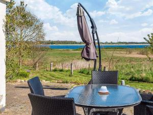 a table and chairs with an umbrella and water at Luxury Seaside Retreat - By Traum Ferienwohnungen in Årøsund