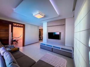 a living room with a couch and a flat screen tv at Beach House Atalaia in Aracaju
