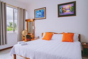a bedroom with a bed with orange pillows and a window at Isla Azul in Puerto Ayora