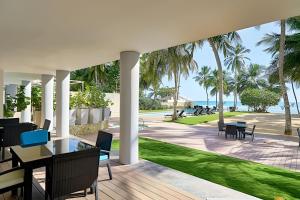 un patio esterno con tavoli, sedie e palme di Beachfront cozy & huge Apartment for family trip a La Puntica de Juan Dolio