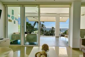 un soggiorno con porte scorrevoli in vetro e vista sull'oceano di Beachfront cozy & huge Apartment for family trip a La Puntica de Juan Dolio