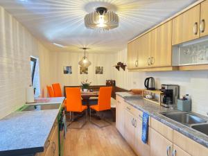 a kitchen with orange chairs and a table in it at Haus Bernstein Apartment 3 in Haus im Ennstal