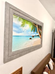 a picture of a beach with a palm tree on a wall at Santa Cosy Villa B Fast Wi-Fi, Netflix Included Split system Air-con & Hot Shower in Santa Rosa