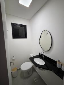 a bathroom with a toilet and a sink and a mirror at Luxury Studio Ubatuba in Ubatuba