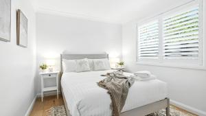 a white bedroom with a bed and a window at The Salty Perch in Callala Beach