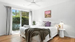 a white bedroom with a bed and a window at The Salty Perch in Callala Beach