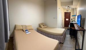 a small room with a bed and a desk with a computer at SplashNStay in Puting Kahoy