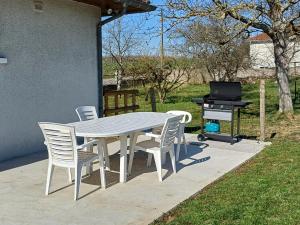 ein weißer Tisch und Stühle mit einem Grill in einem Hof in der Unterkunft Confort en famille proche de Giffaumont - FR-1-611-112 in Braucourt