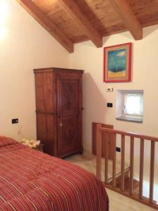 1 dormitorio con 1 cama y armario de madera en Chez Sylvie Vda-Issogne-001, en Issogne