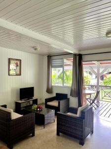 a living room with couches and a tv and windows at Fare Torehau Tiahura in Hauru +21 photos