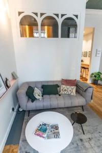 a living room with a couch and a table at Beige Hospitalité - Emma - hypercentre - appart' unique-parking in Saint-Étienne