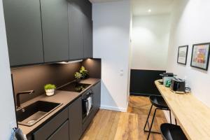 a kitchen with black cabinets and a wooden counter top at Beige Hospitalité - Emma - hypercentre - appart' unique-parking in Saint-Étienne