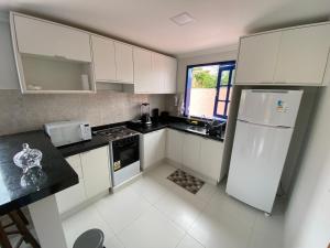 a kitchen with white cabinets and a white refrigerator at Villages Flor de Tangerina in Mucugê