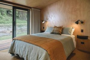 a bedroom with a large bed and a large window at Lakefront Luxury at Okere Falls Lake Rotoiti in Rotorua