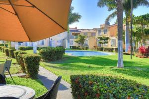 a patio with a table and an umbrella in a yard at Joyas Vallarta Coto Frente a Vidanta Worl in Jarretadera