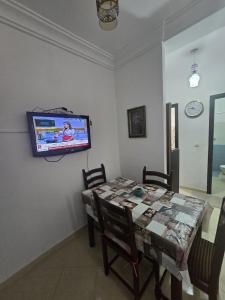 a dining room with a table and a tv on a wall at Martil Riad Sofia in Martil