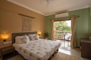 a bedroom with a bed and a balcony with a table at The Palm House in Canacona