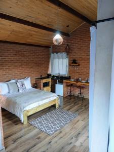 a bedroom with a bed in a brick wall at Chalé Black Touch in Santo Antônio do Pinhal