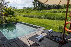 une piscine avec des chaises et un parasol dans l'établissement The Pulu Villas by GenuineHost, à Ubud