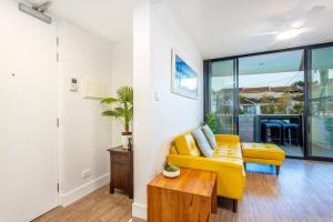 a living room with a yellow couch and a table at Scarborough Pearl Apartment in Perth