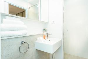 a white bathroom with a sink and a mirror at Scarborough Pearl Apartment in Perth +7 photos