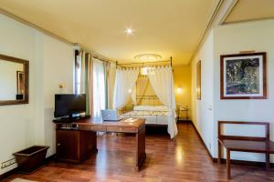 Habitación con escritorio, cama y TV. en Hotel Azofra en Burgos