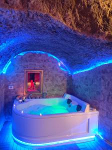 a bath tub in a stone room with blue lights at La grotta romantica in Fabrica di Roma