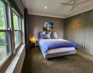 a bedroom with a bed with blue sheets and windows at Family Luxury In Lake Wendouree in Wendouree +24 photos