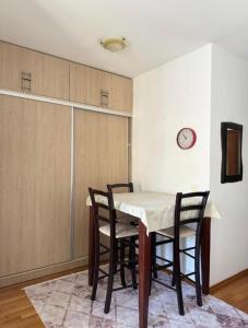 Una mesa de comedor con sillas y un reloj en la pared. en Serenity Studio House, en Budva