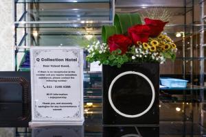 a vase of flowers on a table with a sign at Q Collection Macalister formerly known as Apple Hotel Penang in George Town