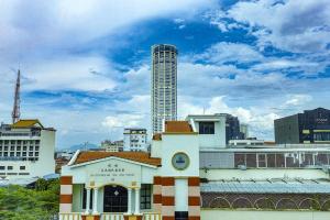 a building with a clock tower in front of a city at Q Collection Macalister formerly known as Apple Hotel Penang in George Town