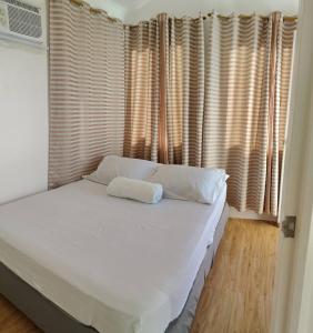 a bedroom with a bed with white sheets and windows at Avida 3-Bedroom Vacation House with Pool in Minuluang