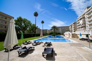 una piscina con sillas y sombrillas junto a un edificio en AQUAMARINA C HomeStay By Turismar, en La Pineda