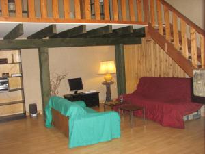 ein Wohnzimmer mit einem roten Sofa und einer Treppe in der Unterkunft Duplex Carreyrou in Beaumont-du-Périgord