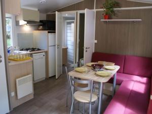 a small kitchen with a table and a pink couch at Mobil-home confortable avec terrasse pour 4 personnes à Meyrueis - API-1-52-181 in Meyrueis