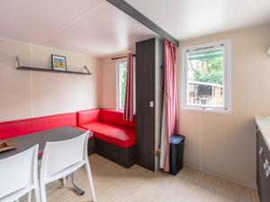 a living room with a red couch and a table at Mobil Home - Terrasse, 1 Chambre, Cuisine Équipée - API-1-52-270 in Bormes-les-Mimosas