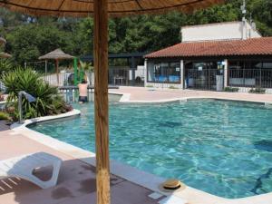 a swimming pool with an umbrella and a person in the background at Mobil Home - Terrasse, 1 Chambre, Cuisine Équipée - API-1-52-270 in Bormes-les-Mimosas
