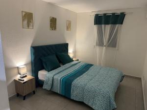 a bedroom with a bed with a green comforter at L'ile aux couleurs in Les Abymes