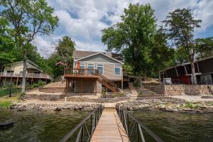 a house on the water with a wooden bridge at Charming Waterfront Cabin - Sleeps 10 in Rocky Mount
