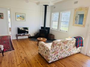 a living room with a couch and a wood stove at Beltane Cottage in Canyon Leigh