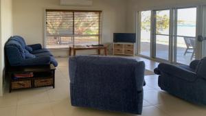 a living room with two blue chairs and a television at The Beach House - Spectacular Location - Privacy - Right On The Beach in Coffin Bay