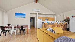 a living room with a yellow couch and a kitchen at Sheoak Holiday Home in Coffin Bay